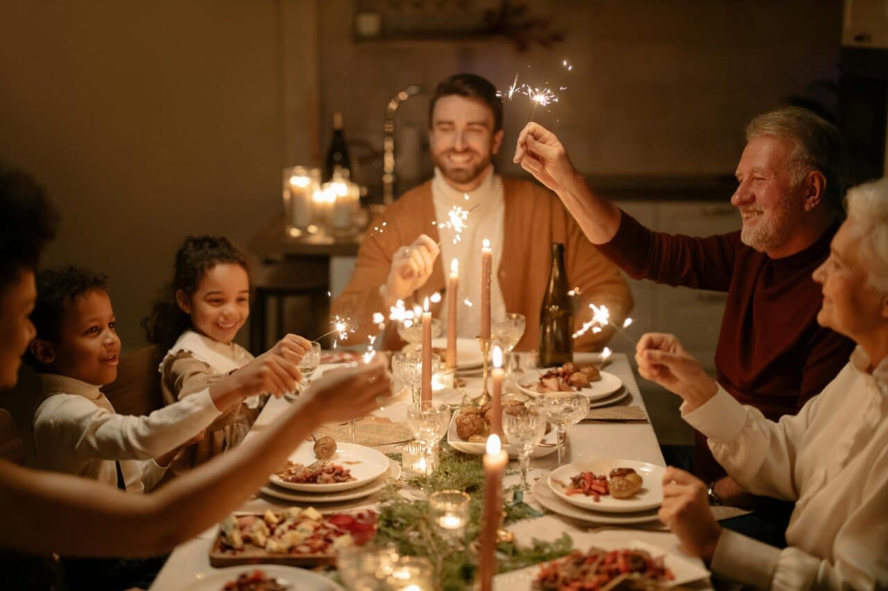 Family enjoying holiday meal with candles on table.